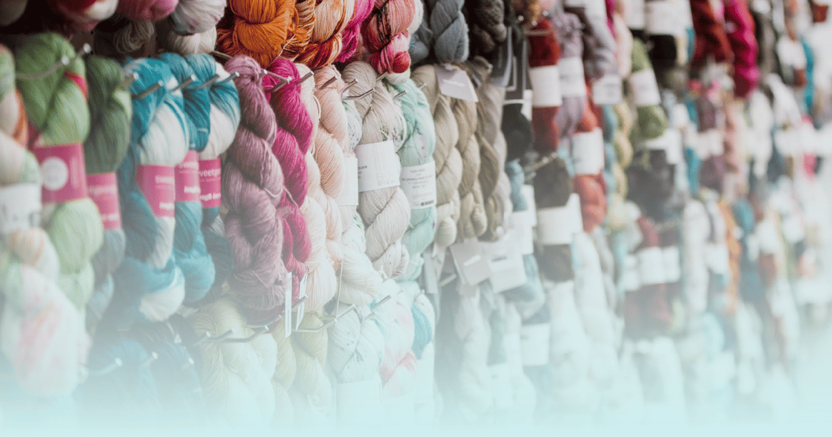 Yarn wall at Pintuck & Purl with a teal fade layer of color from the bottom